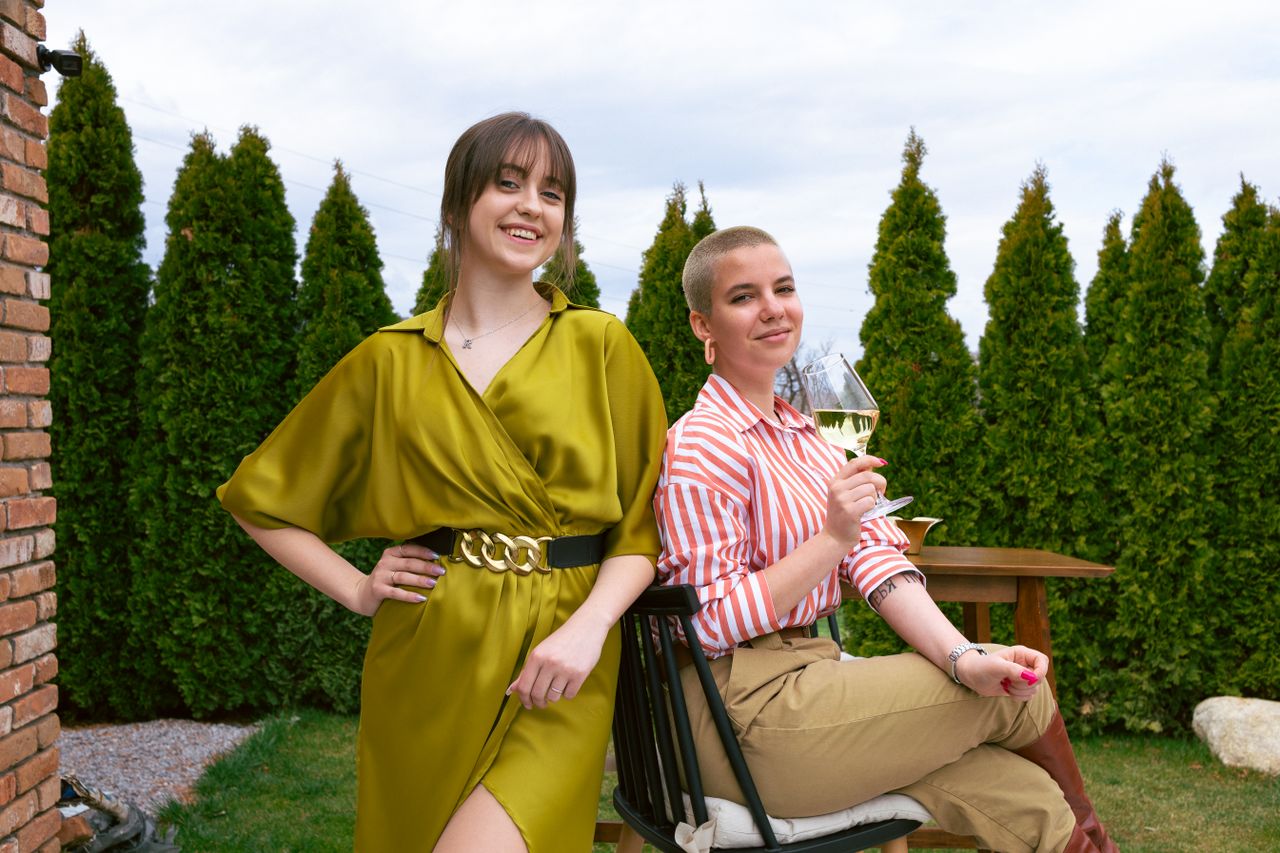 Two women enjoying a relaxing time outdoors, sharing smiles and wine.